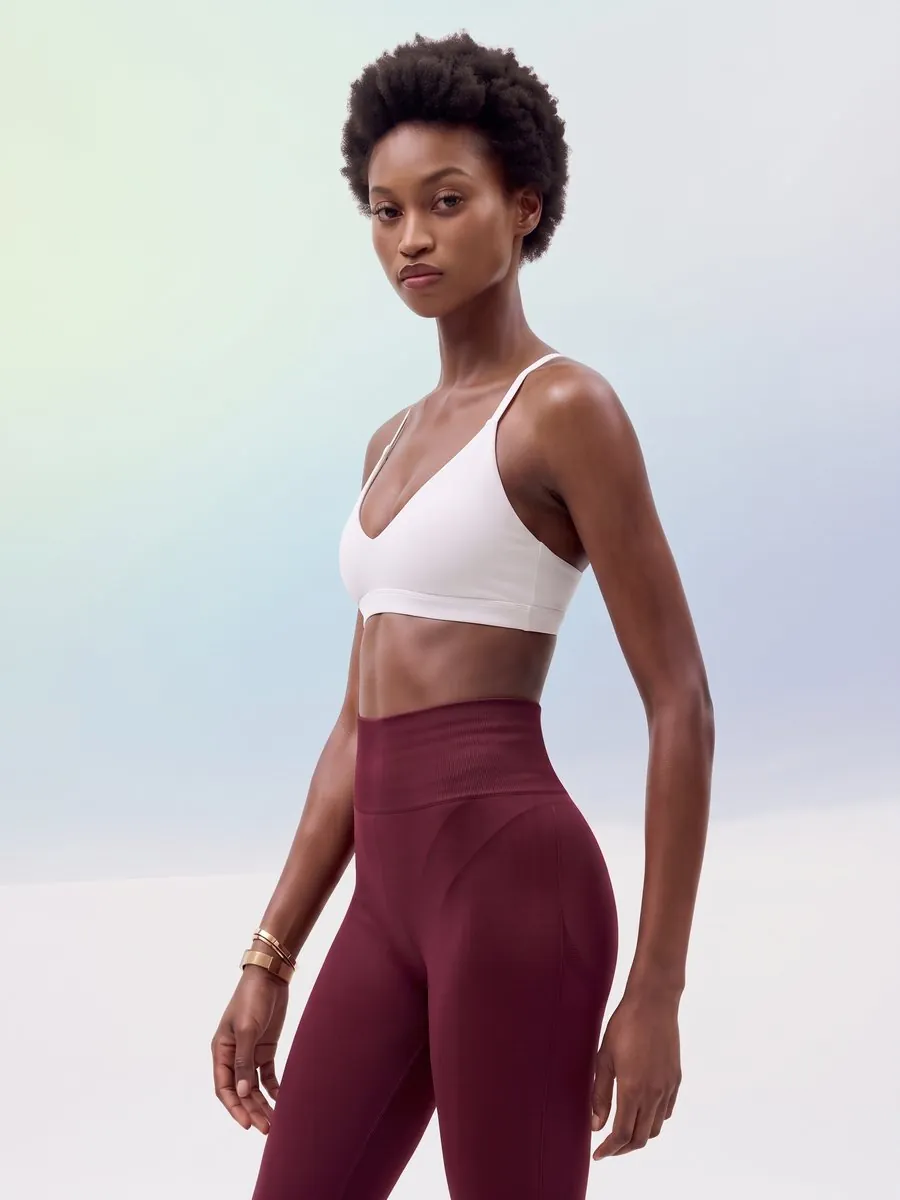 Fashion product visual: model in a white sports bra and burgundy leggings