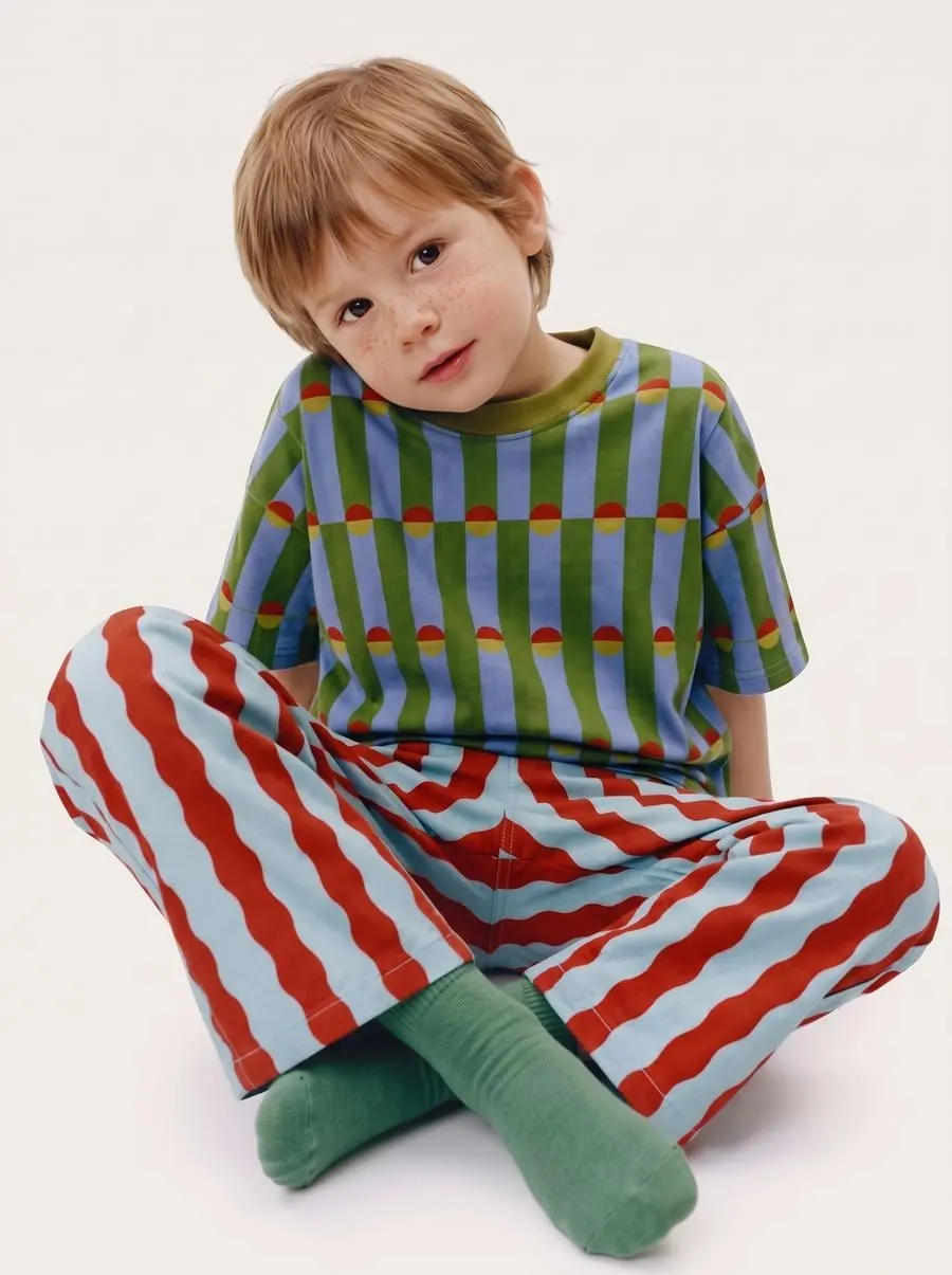 Child model sitting on a white background wearing the outfit